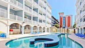 Un hôtel doté d’une piscine, de plusieurs balcons et d’une tour rouge remarquable.
