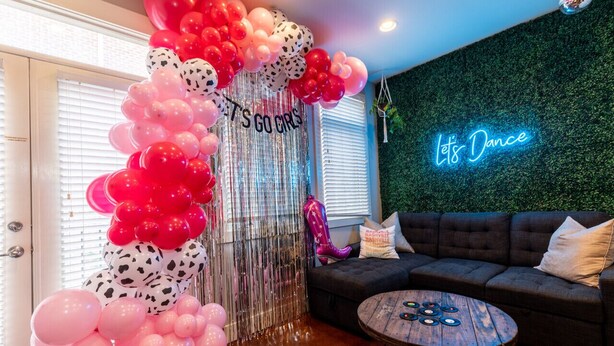 A room with a decorative balloon arch, a neon sign, a sofa, and a coffee table. - The Celebrity - Free Parking, Central, Vanderbilt (Nashville)