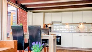 Uma cozinha moderna com armários brancos, uma área de jantar com mesa e cadeiras, e piso de madeira.