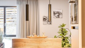 A modern interior with a wooden dining table, pendant lights, and framed pictures on the wall.