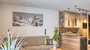 A modern living room with a sofa, a round wooden coffee table, and a potted plant.