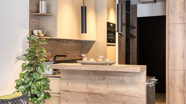 A modern kitchen with wooden cabinetry, pendant lighting, and a central island.
