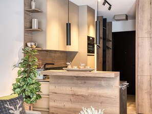 Eine moderne Küche mit Holzschränken, Pendelleuchten und einer zentralen Kochinsel.