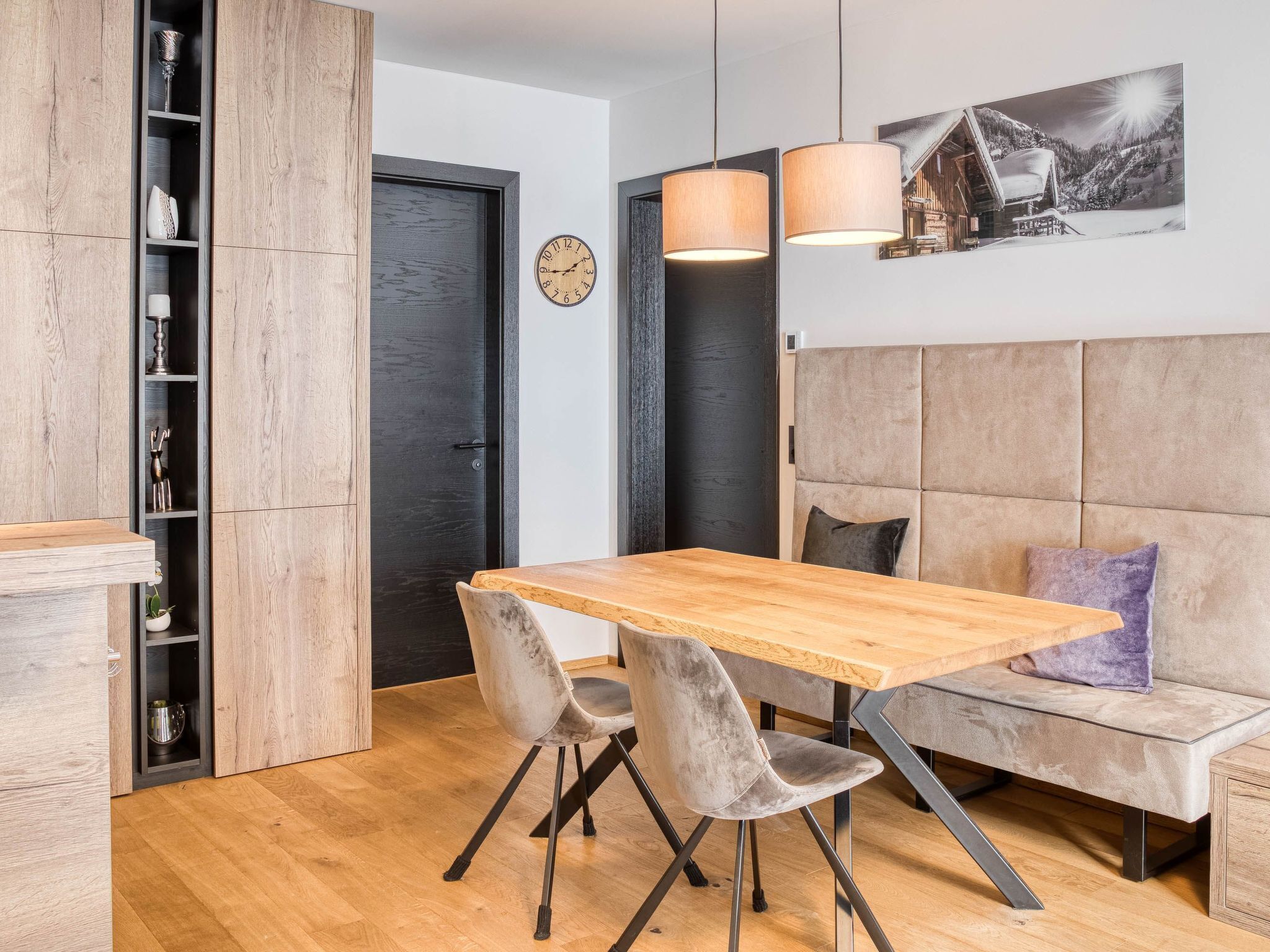 Una cocina moderna con una mesa de madera, dos sillas, un sofá y un reloj en la pared.