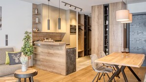 A modern kitchen with wooden cabinetry, a dining area with a wooden table and chairs, and a large window overlooking a body of water.