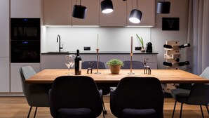 A modern kitchen with a wooden dining table, black chairs, pendant lights, and a wine rack. - Stillvolle Luxus Wohnung in der Residenz Silvretta by Interhome (See)