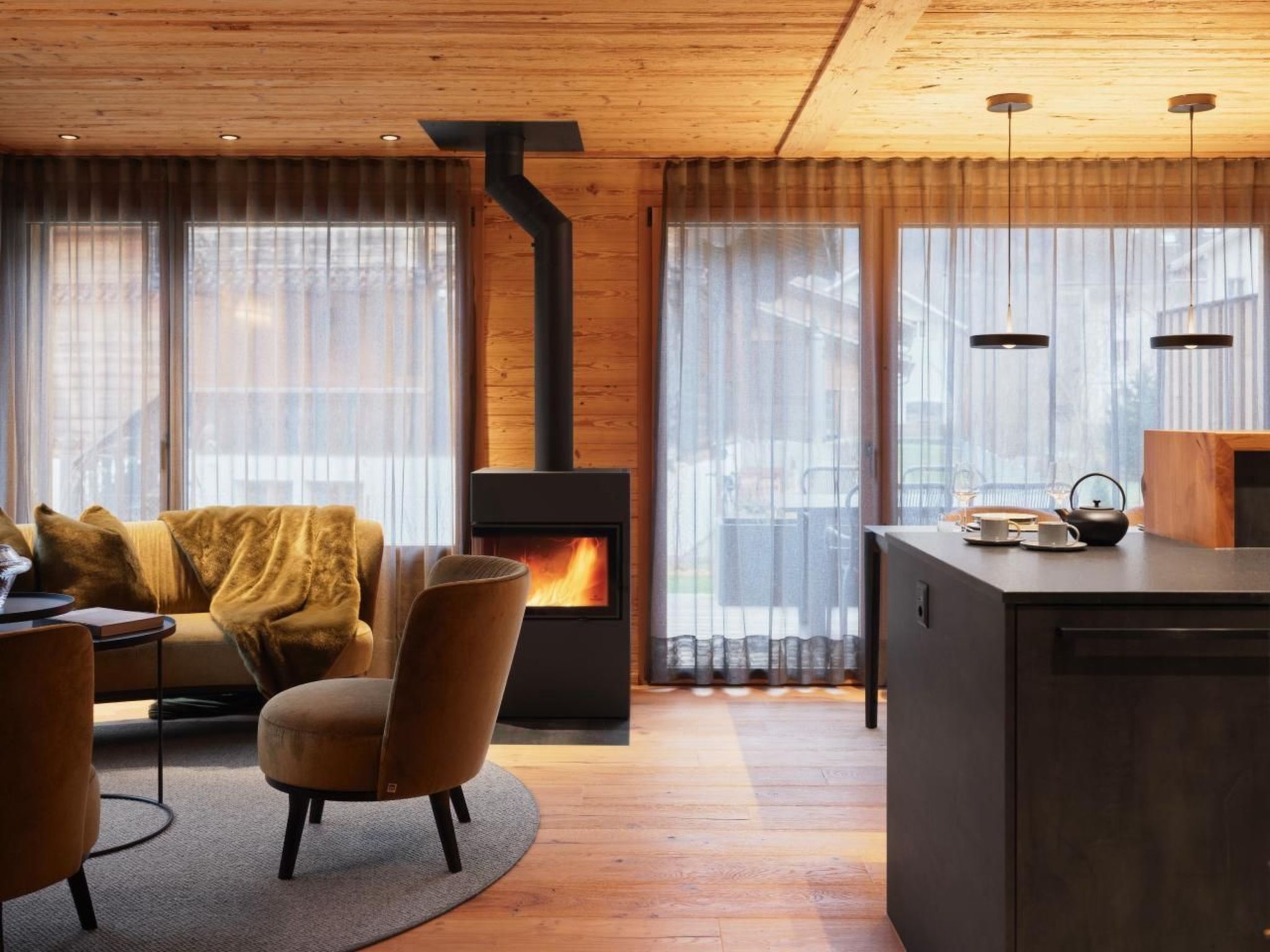 Un salon moderne avec une cheminée, un canapé, un fauteuil et une petite table sur laquelle se trouve une bouilloire.
