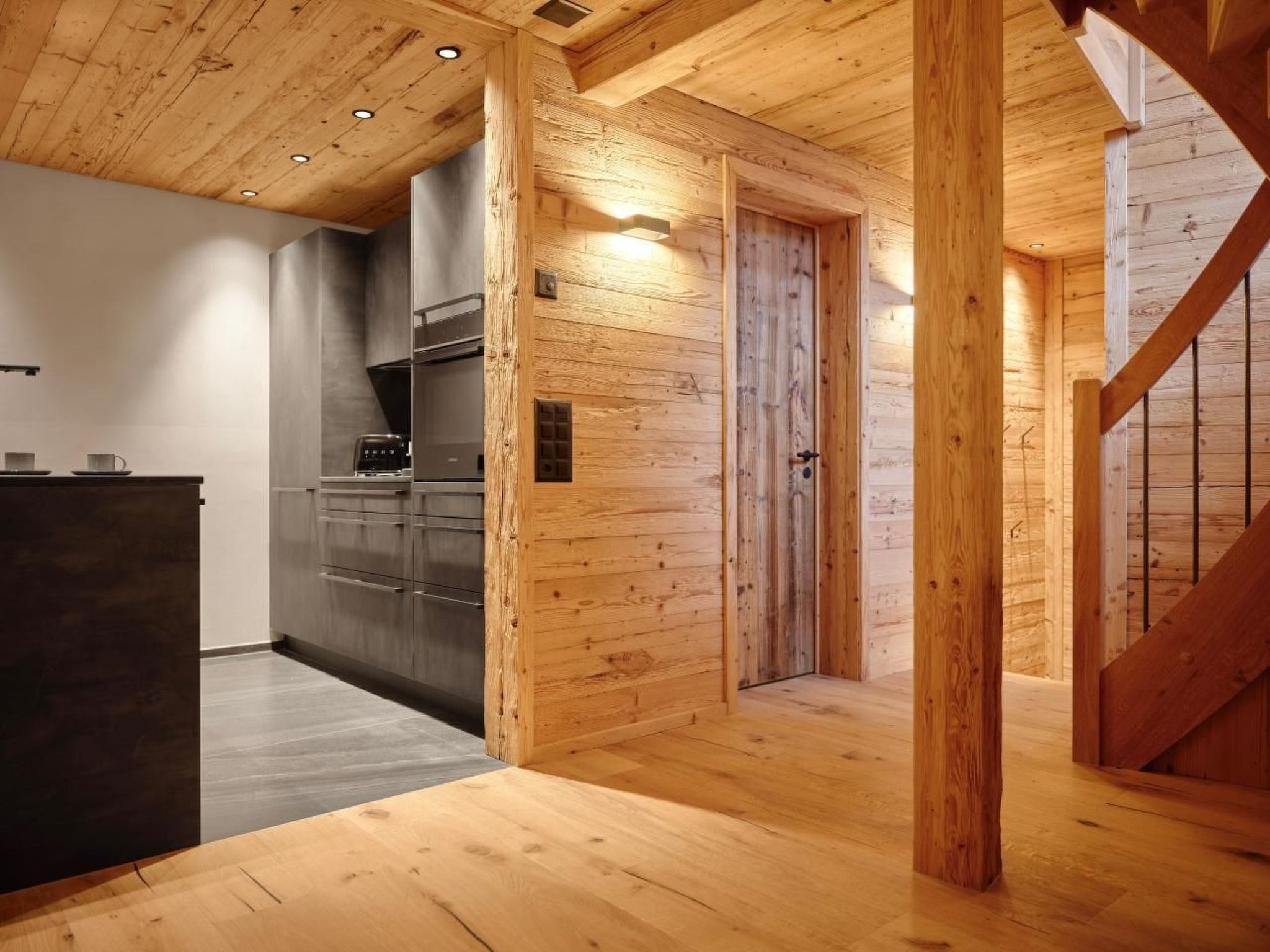 Une cuisine moderne avec des murs en bois et un plan de travail foncé.
