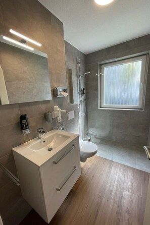 A modern bathroom with a large sink, toilet, and shower. - Kernsanierte Ferienwohnung in zentraler Lage by Interhome (Wilhelmshaven)