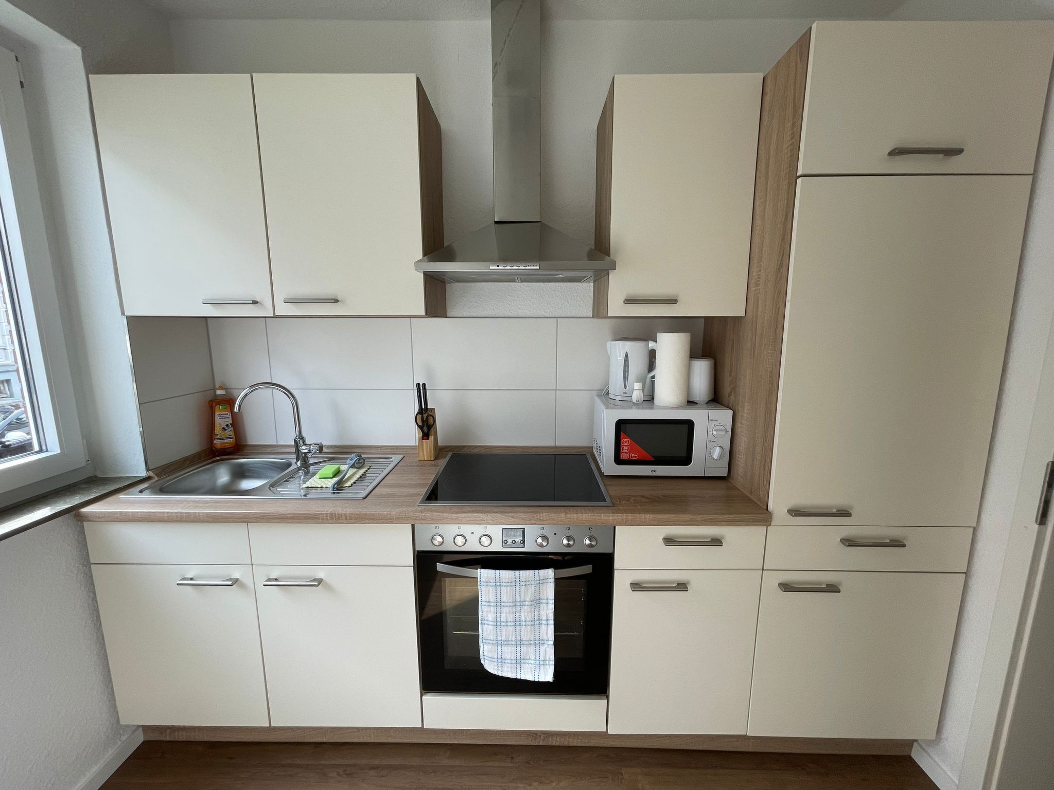 A compact kitchen with a sink, microwave, oven, and cabinets.