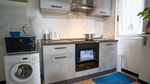 Een koelkast, een magnetron, een oven, kookgerei, borden en bestek