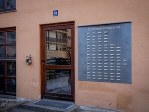 A building entrance with a door and a sign listing apartment numbers. - Come4Stay Passau - Holzheim 126 - Parkplatz by Interhome (Passau)