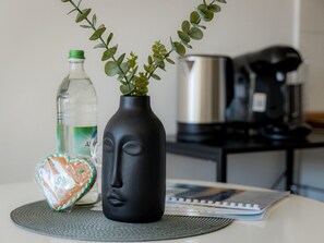 A table with a black vase containing green plants, a water bottle, a heart-shaped cookie, and a notebook. - Come4Stay Passau - Holzheim 126 - Parkplatz by Interhome (Passau)