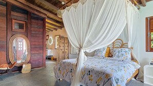 Una habitación con una cama bajo un dosel, un espejo y techo de madera.