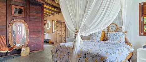 A room with a bed under a canopy, a mirror, and a wooden ceiling.