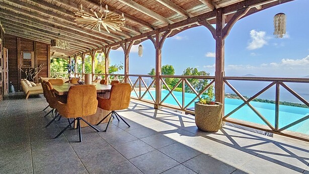 Un espacio comedor al aire libre con techo y vistas al océano.