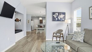 A modern living room with a glass coffee table, a grey sofa, and a world map artwork on the wall. - Lux Ft Walton Beachfront Home MINS to HCA Florida Hospital/ Sleeps 4/ King Bed (Fort Walton Beach)
