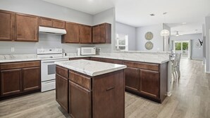 A modern kitchen with dark wooden cabinets, white marble countertops, and stainless steel appliances. - Lux Ft Walton Beachfront Home MINS to HCA Florida Hospital/ Sleeps 4/ King Bed (Fort Walton Beach)