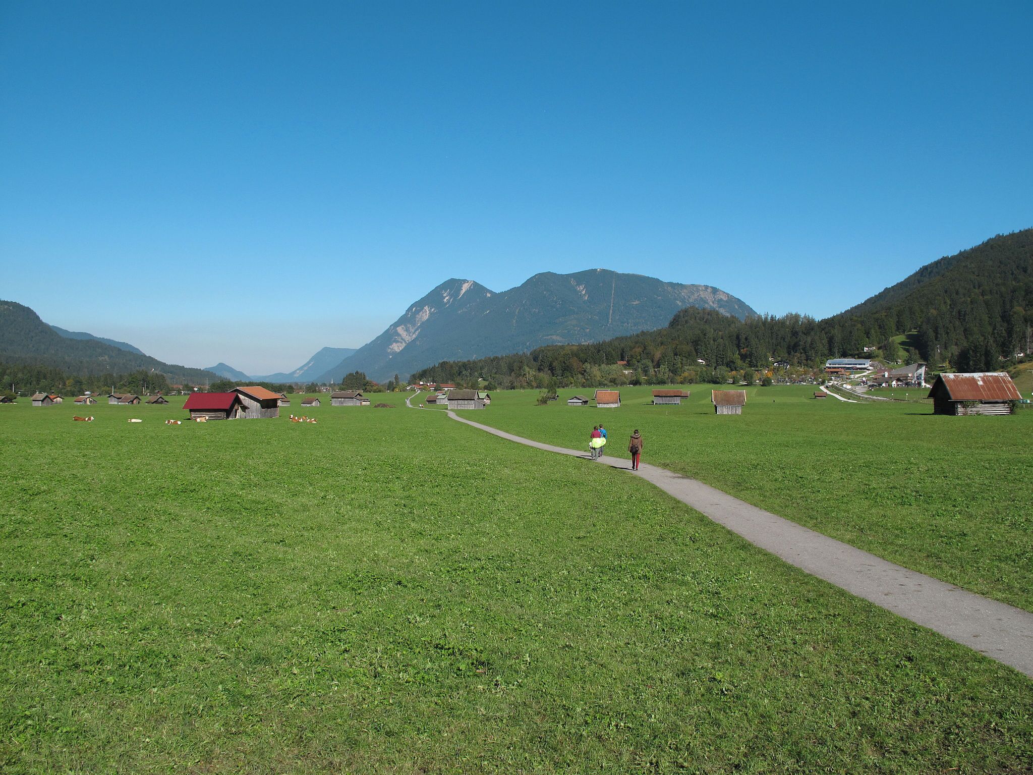 Un paisaje rural con cielo despejado, campos verdes y edificios dispersos.
