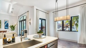 A modern kitchen with a stainless steel sink, a built-in dishwasher, and a countertop with toiletries. - The Rendez-Vous Villa (Fort Lauderdale)