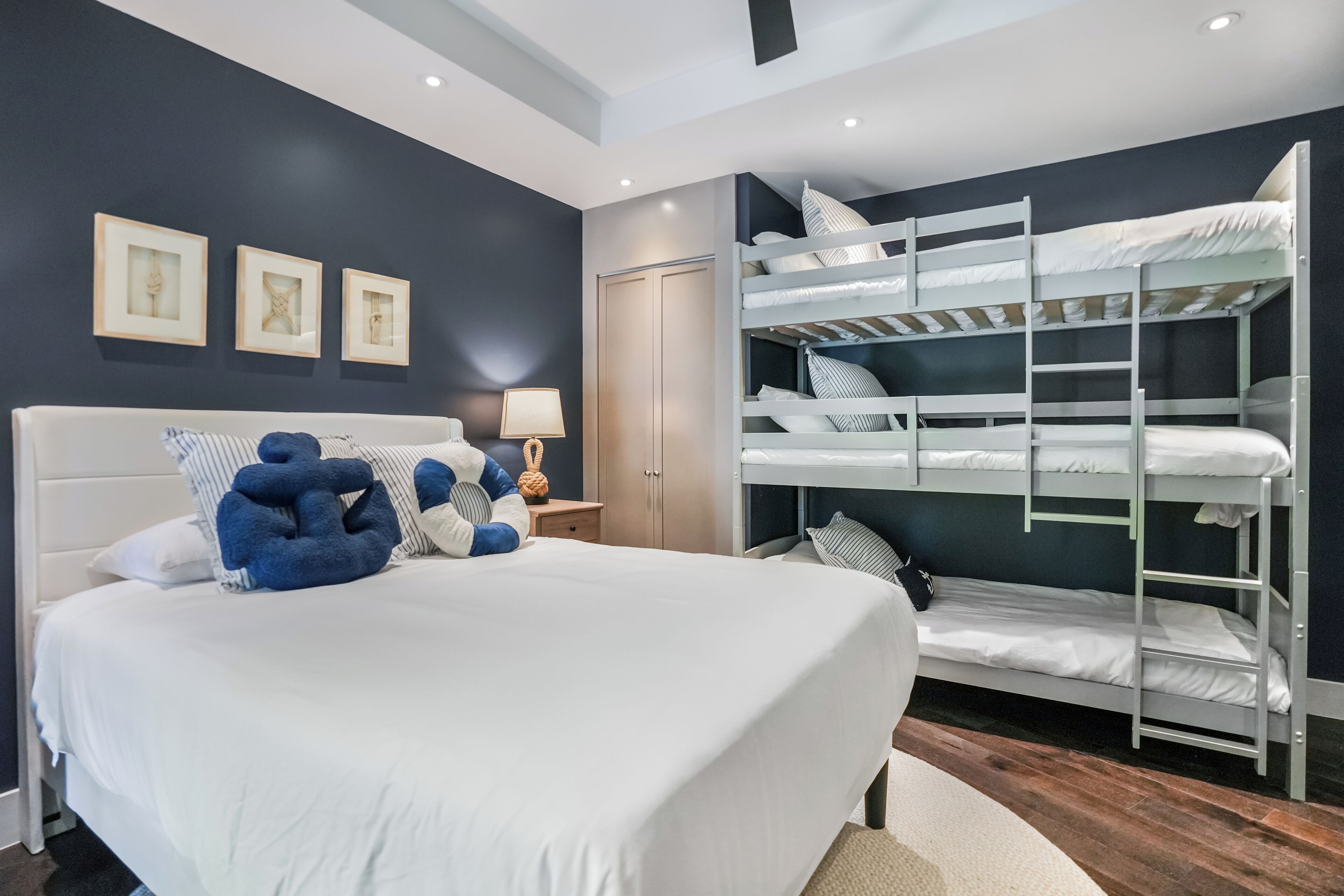 Un dormitorio moderno con una cama grande, literas y cuadros en la pared.