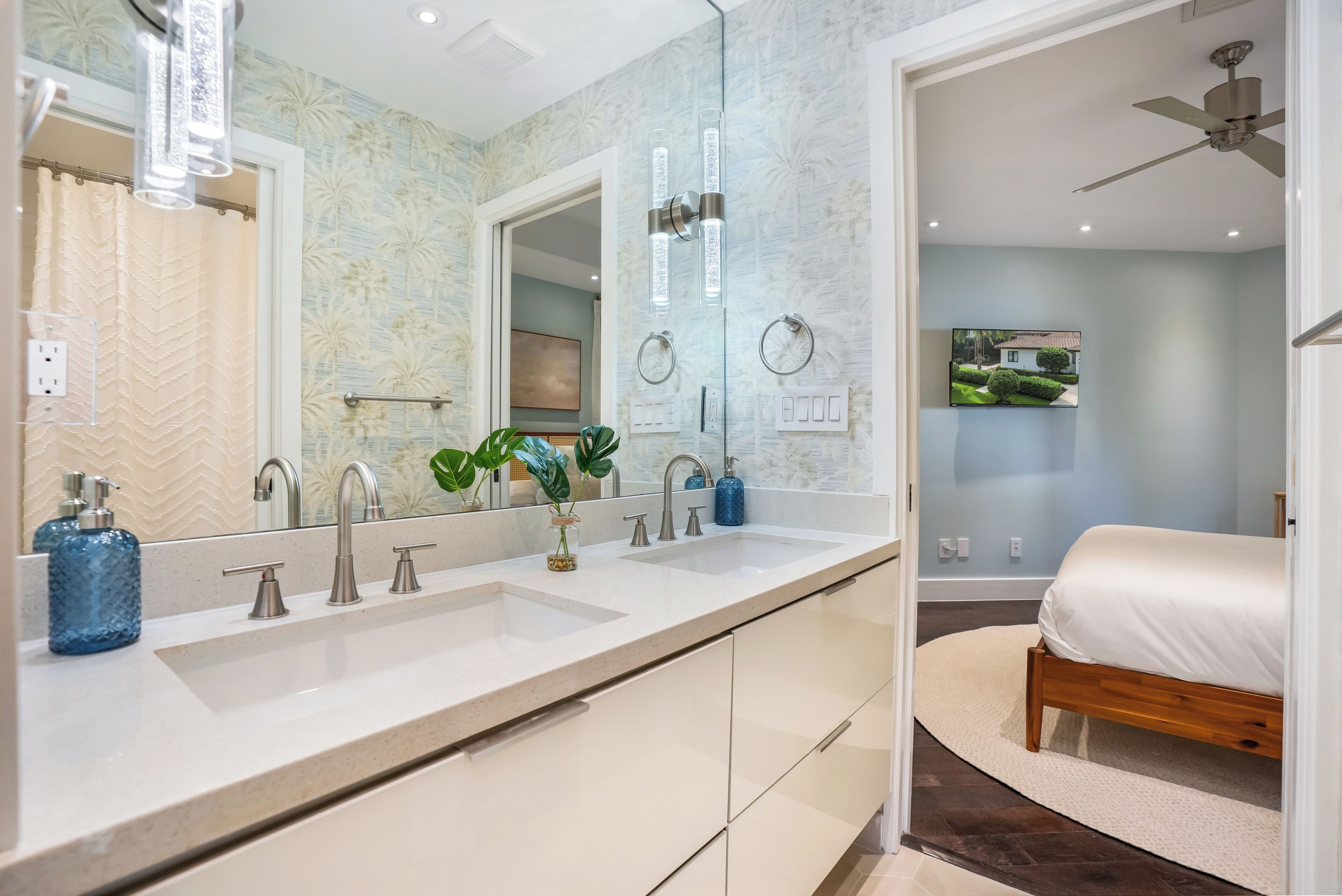A bathroom with a double sink, two mirrors, a ceiling fan, and a shower curtain.