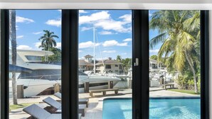 A view of a swimming pool with lounge chairs and a dock with boats. - The Rendez-Vous Villa (Fort Lauderdale)