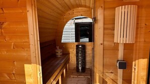 Een houten interieur met een bank, een kachel en een raam.