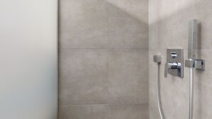 Une salle de bain équipée d’une douche, d’un panneau de commande et d’un porte-serviettes fixé au mur.