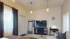 Une chambre d’hôtel moderne équipée d’un lit, d’un canapé, d’une télévision, d’un bureau et d’une petite table.