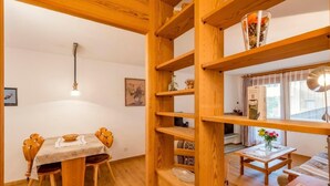 Un'area pranzo in legno con un tavolo e sedie, una libreria in legno e un tavolino con un vaso di fiori.