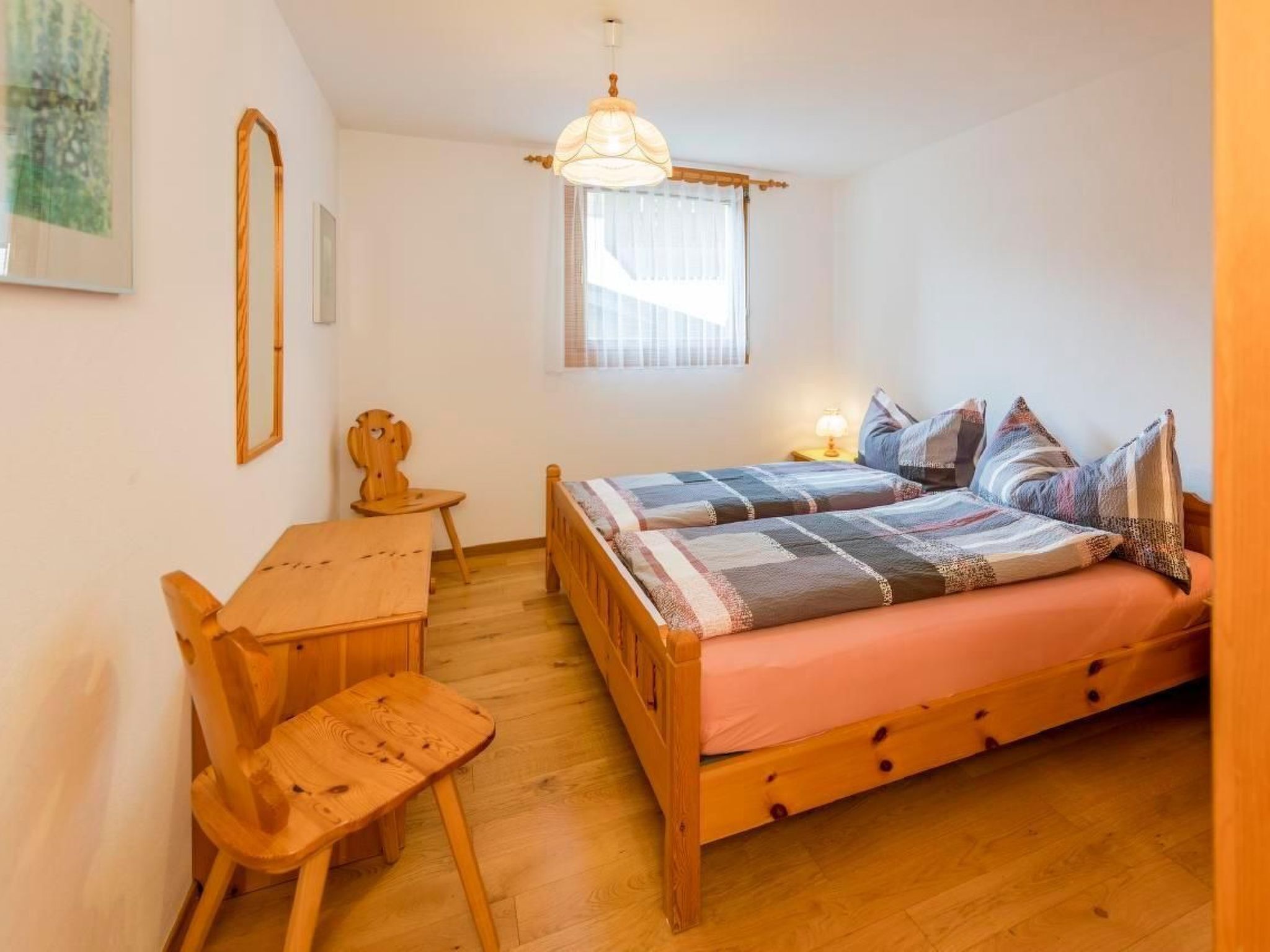 Ein kleines, gemütliches Schlafzimmer mit einem Holzbett, einem Schreibtisch und einem Stuhl.