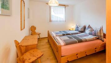 Ein kleines, gemütliches Schlafzimmer mit einem Holzbett, einem Schreibtisch und einem Stuhl.