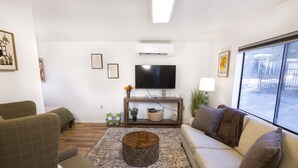 Een woonkamer met een bank, fauteuil, salontafel, televisie en een raam met uitzicht.
