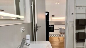 Un bagno moderno con un lavandino bianco, uno specchio e un porta asciugamani.