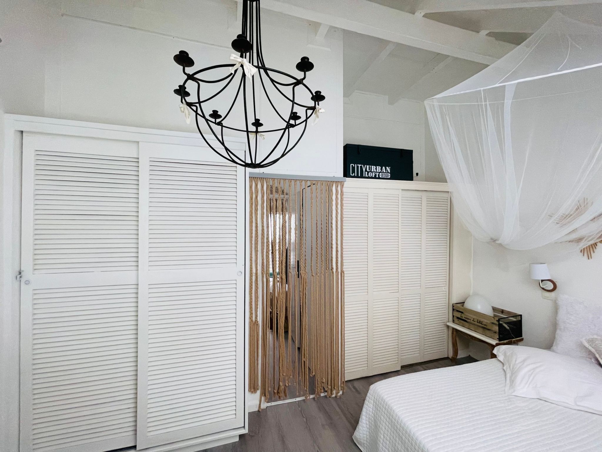 A bedroom with a bed, a chandelier, a wardrobe, and a sign on the wall.