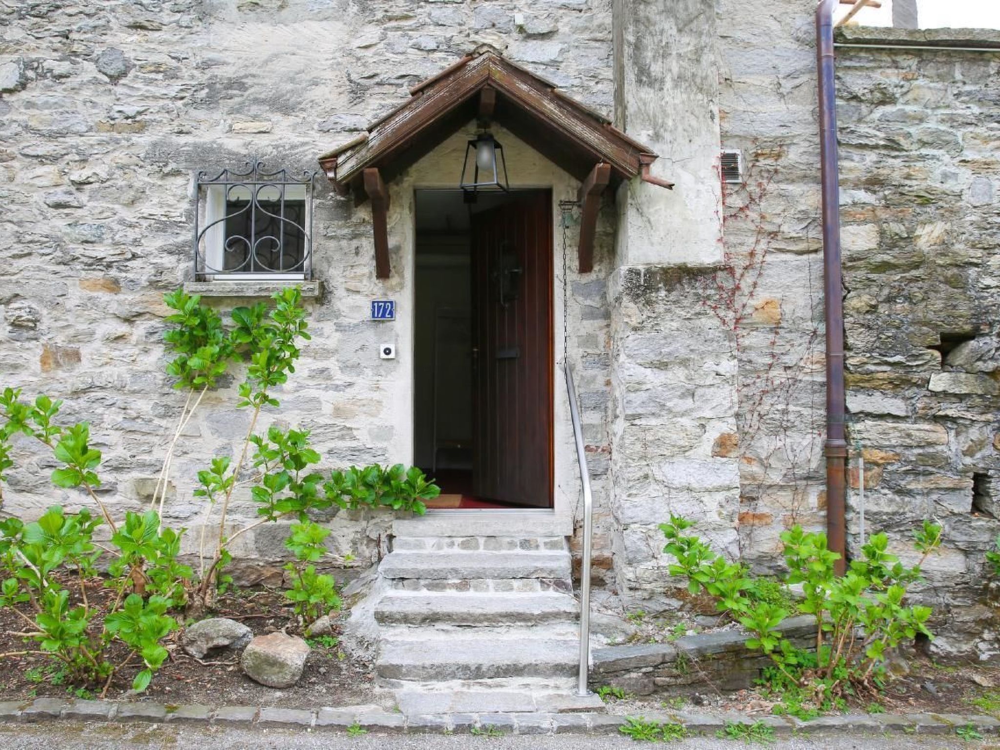 Ein Steinhaus mit einer Holztür und Stufen, die zu einer kleinen Veranda führen.