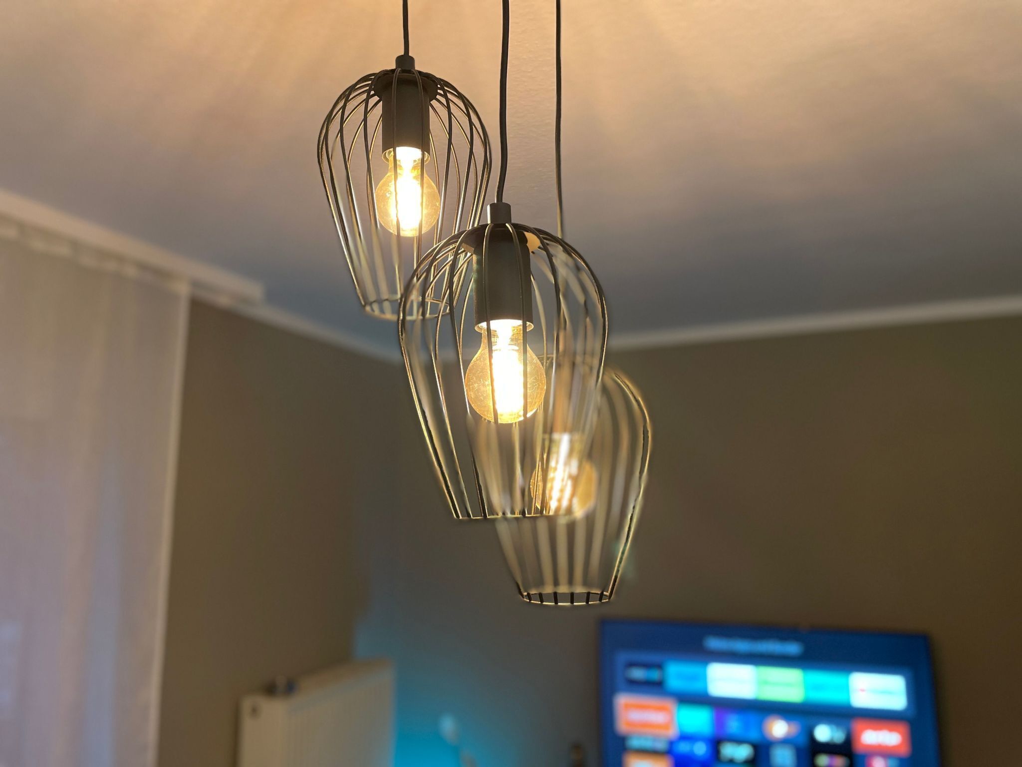 En modern inredning med en hängande lampa med tre ljuskällor.