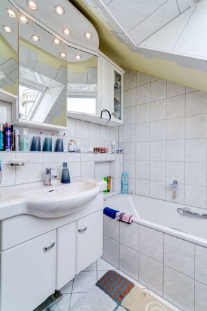 A modern bathroom with a white sink, mirror, and vanity, a bathtub, and a shower area. - ApartmentmitAusblick by Interhome (Wörth)