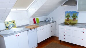 A kitchen with white cabinets, a sink, a dishwasher, and a wooden cutting board. - ApartmentmitAusblick by Interhome (Wörth)