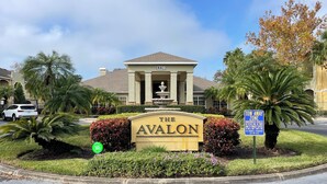 Placa para "The Avalon", com entrada por portão, uma fonte e uma placa de "Zona de Reboque".