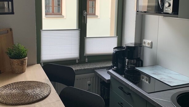Una cucina compatta con finestra, un forno a microonde, una moka e un piccolo angolo ristoro con una panca.