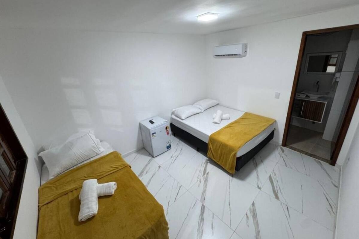 A small, clean room with two beds, a bedside table, a heater, and a mirror.