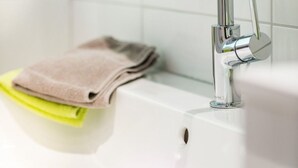 Un baño moderno con grifo cromado, lavamanos blanco y barra para toallas.