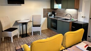 Una cocina compacta con comedor, un televisor montado en la pared y una pequeña mesa con sillas.