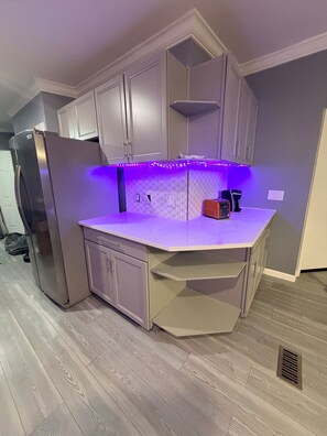 A modern kitchen with a built-in island, grey cabinets, and under-cabinet LED lighting.