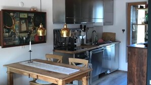 Una cocina rústica con vigas de madera, una mesa de comedor con bancos y electrodomésticos de acero inoxidable.