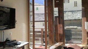 Habitación con televisión, una mesa de madera, una mesa de vidrio y vista a un paisaje nevado a través de amplias puertas de cristal.