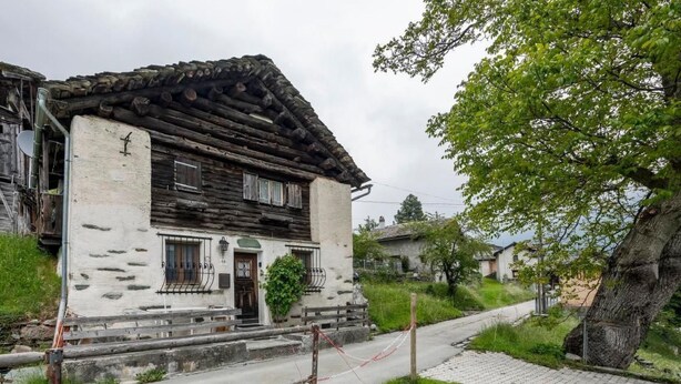 A rustic stone house with a steeply pitched roof, wooden steps leading to the entrance, and a small garden area. - Casa Tavernela by Interhome (Vicosoprano)