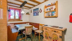 A cozy room with a wooden bench, a table, and a cabinet with floral designs. - Casa Tavernela by Interhome (Vicosoprano)